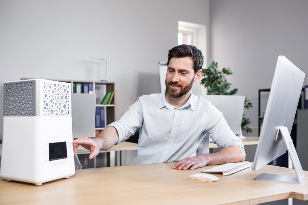 Happy businessman works in office hot, turns on portable small air conditioner