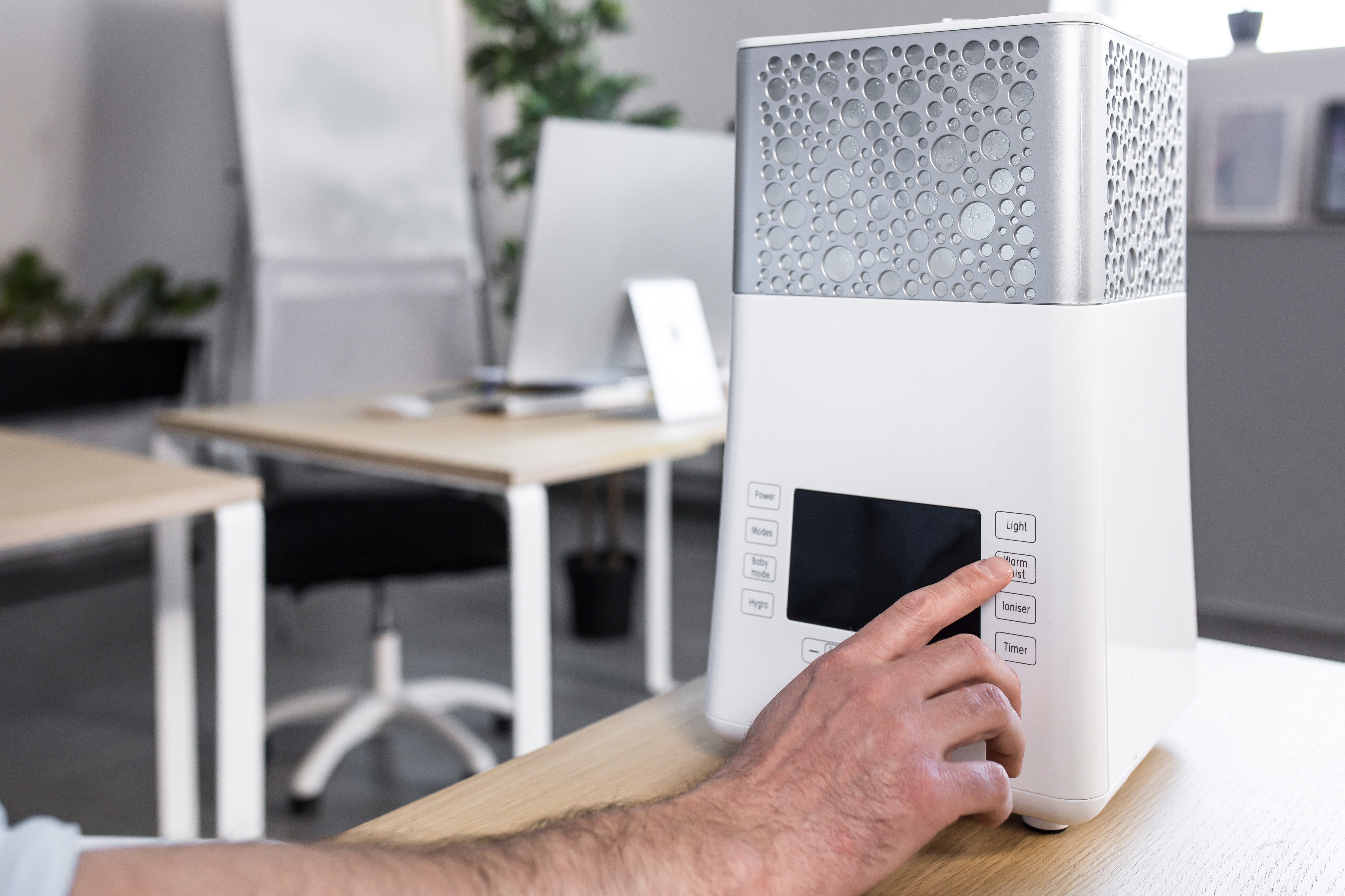 Close up photo. A man's hand that includes a desktop humidifier or air conditioner