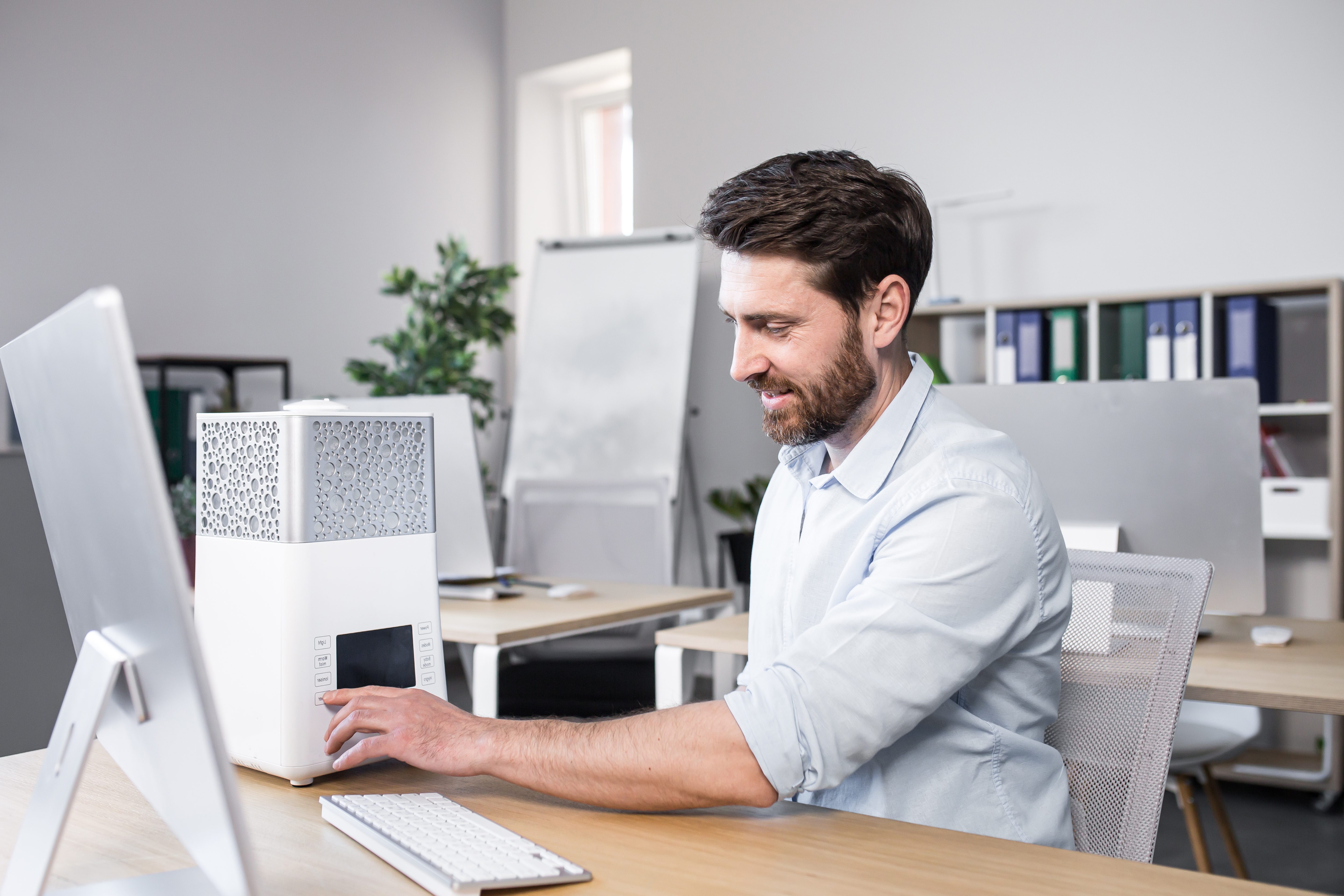 Happy businessman works in office hot, turns on portable small air conditioner