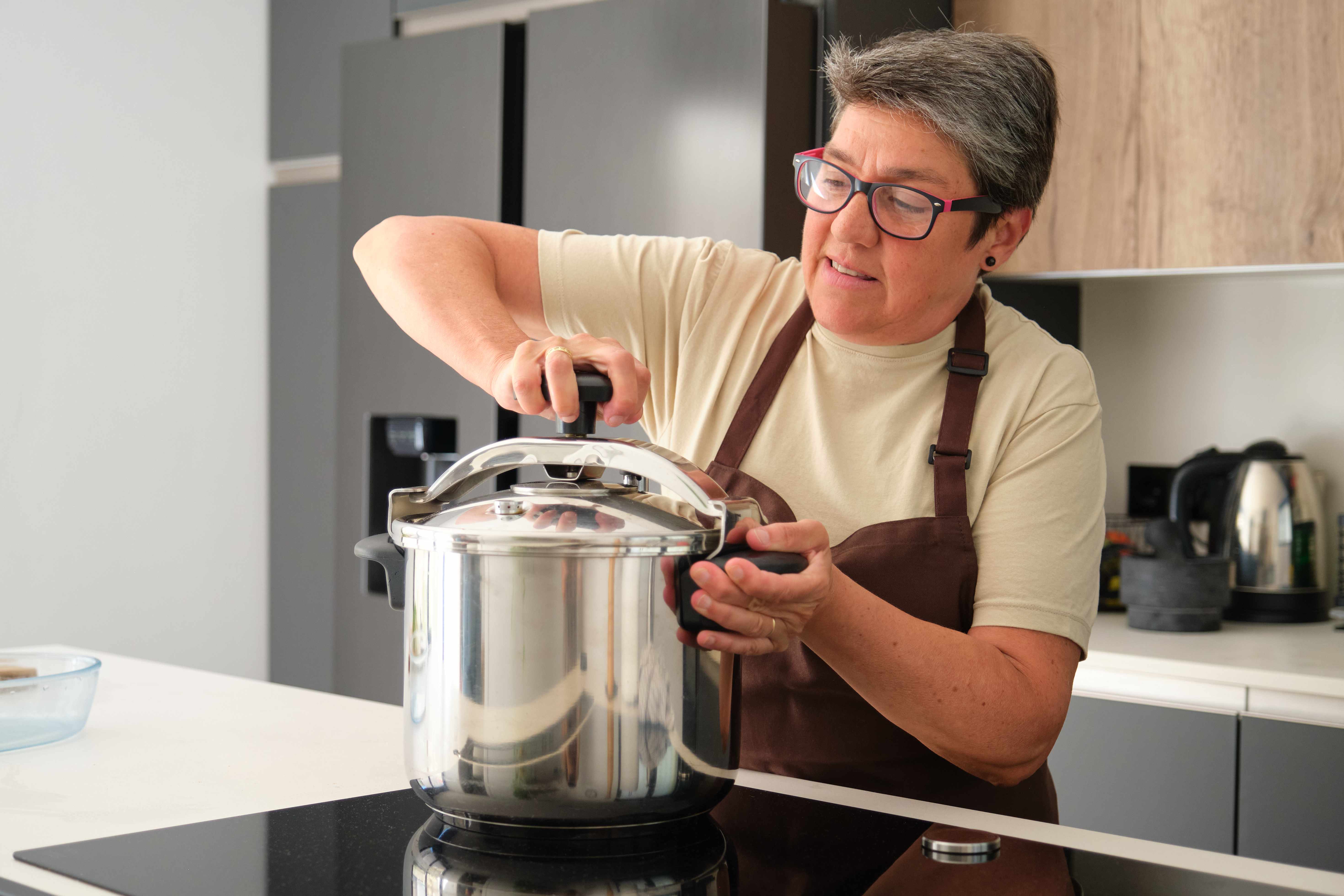 Mature Spanish woman closing a pressure cooker.