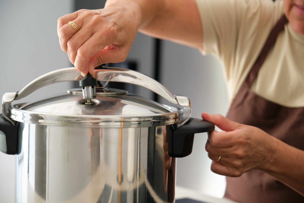 Mature Spanish woman placing regulator whistle on pressure cooker.